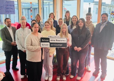 Gruppenbild mit Schild zur offiziellen Aufnahme in das Netzwerk „Schule ohne Rassismus – Schule mit Courage“
